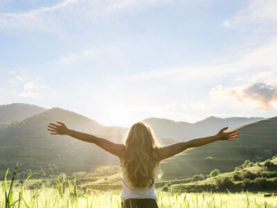 woman in nature with hands outstretched having a beautiful fresh morning