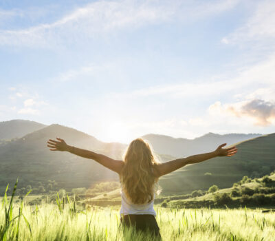 woman in nature with hands outstretched having a beautiful fresh morning