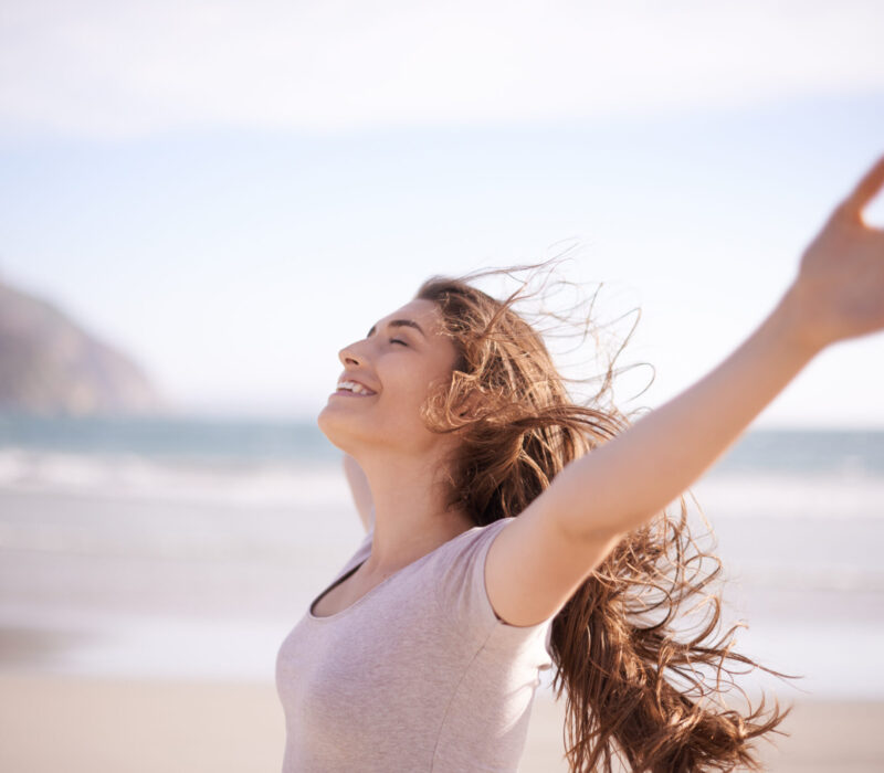 Shot of a beautiful young woman standing with her arms outstretched on the beach